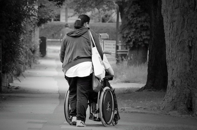 žena vezoucí invalidní vozík